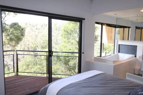 a bedroom with a tub and a large window with a view of a balcony at Luxurious, Tranquil and Private in Lindisfarne