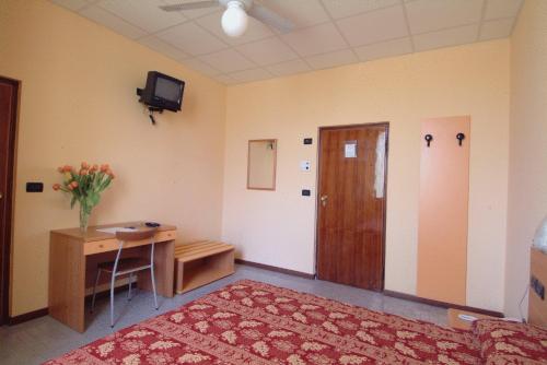 a room with a bed and a desk and a television at Hotel San Geminiano in Modena
