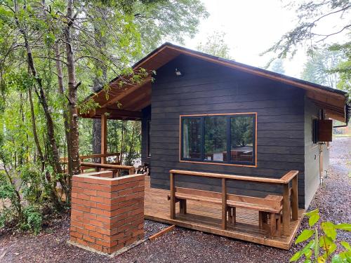 ein schwarzes winziges Haus mit einer Bank auf dem Deck in der Unterkunft Cabaña nueva en Pucón in Pucón