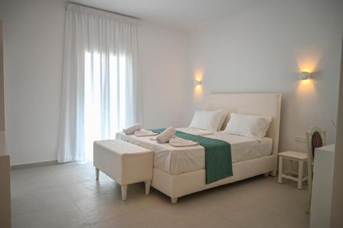 a white bedroom with a bed and a window at Levanta guesthouse in Schinoussa