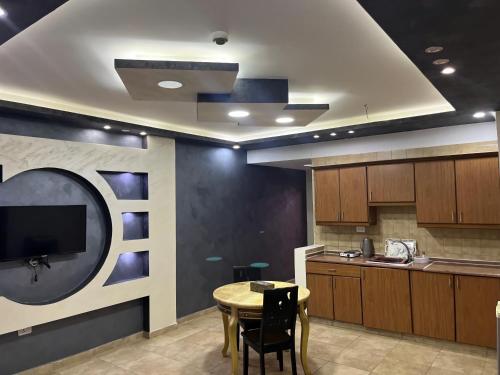 a kitchen with a table and a tv on a wall at Shihan hotel suites in Amman