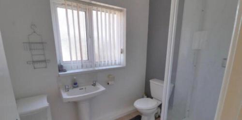 a bathroom with a sink and a toilet and a window at Cosy House Relaxing Rooms close to all amenities 