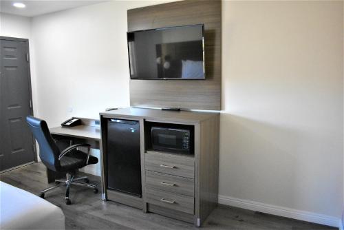 a room with a desk and a tv on a wall at Signature Anaheim Maingate in Anaheim