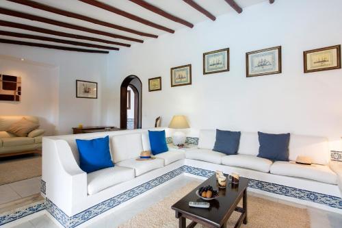 een woonkamer met witte meubels en blauwe kussens bij Villa Tupi by Villa Plus in Boliqueime