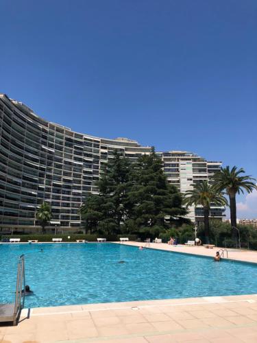 ein großer Pool vor einem großen Gebäude in der Unterkunft Cannes Marina Résidence Le Surcouf - Studio de 28m2 au 10ème étage avec piscine, terrasse, parking, vue montagne et port : Mandelieu-La Napoule in Mandelieu-la-Napoule