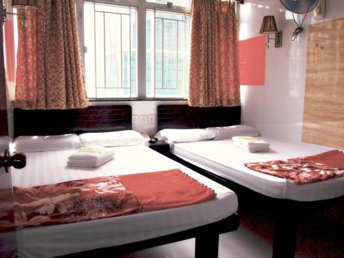 two beds in a room with windows and curtains at Australia Lounge in Hong Kong