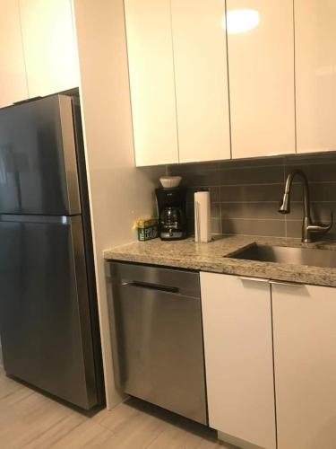 a kitchen with white cabinets and a stainless steel refrigerator at Bekahouse Hostel with parking, backyard and laundry in Miami