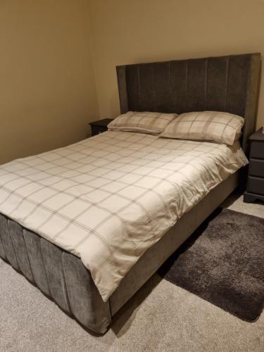 a bedroom with a large bed with a brown headboard at Fabulous Home from Home - Central Long Eaton - Lovely Short-Stay Apartment - HIGH SPEED FIBRE OPTIC BROADBAND INTERNET - HIGH SPEED STREAMING POSSIBLE Suitable for working from home and students Very Spacious FREE PARKING nearby in Long Eaton