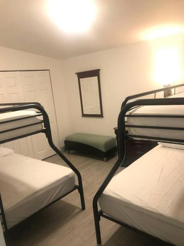 a room with three bunk beds and a mirror at Bekahouse Hostel with parking, backyard and laundry in Miami