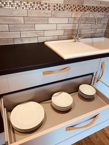 a kitchen with a sink and four white plates at Plumptons Farm Holiday Lodges in Colchester