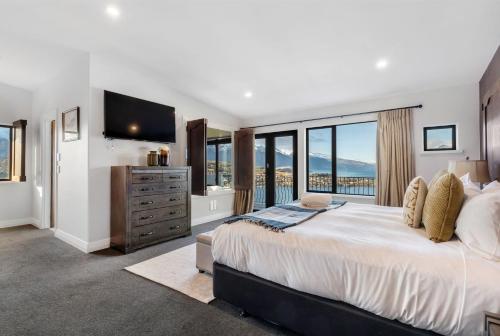a bedroom with a large bed and large windows at The Star of Queenstown Hill in Queenstown