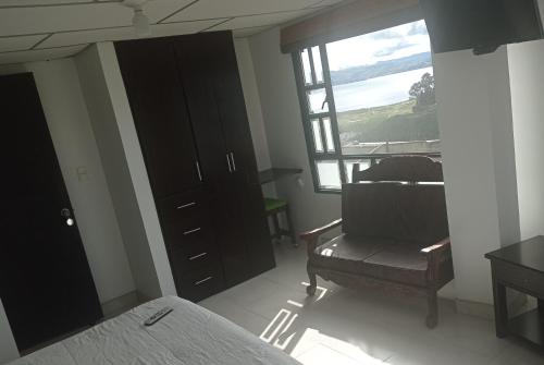 a bedroom with a bed and a chair and a window at Refugio Turistico & Restaurante Dylam in Aquitania