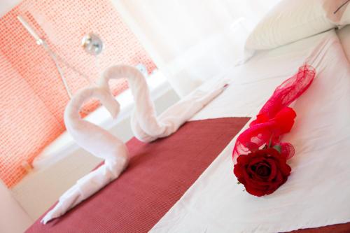 une rose rouge et un lit blanc avec un cœur et une fleur dans l'établissement Minihotel IRIS, à Maiori