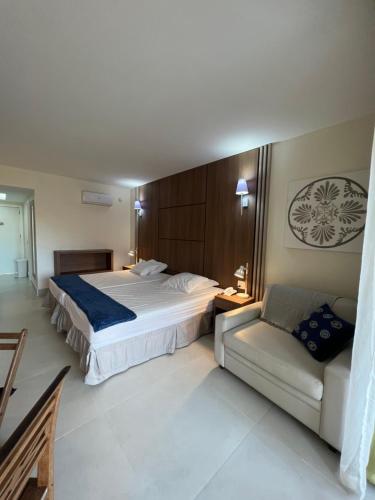 um quarto de hotel com uma cama e um sofá em Buzios Beach Resort Residencial super luxo 1307 em Búzios