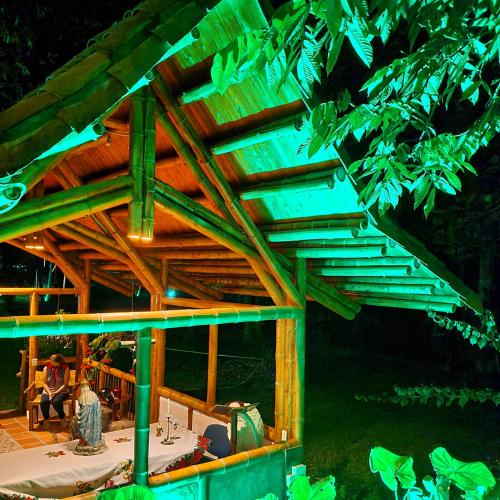 a wooden pergola with a table on a deck at night at El Percal Hacienda Hotel in Montenegro