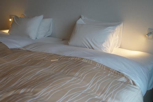 a bed with white sheets and pillows in a room at SETOUCHI SUP RESORT - Ao - in Shodoshima