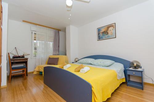 a bedroom with a bed with a yellow blanket and a chair at Apartment Andy in Komiža