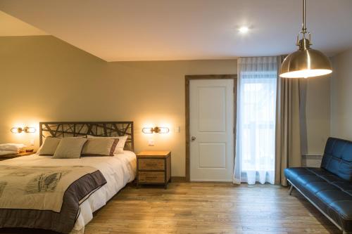 a bedroom with a bed and a blue couch at Hotel "Le Suisse" in Saint-Donat-de-Montcalm