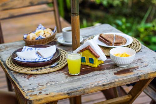 einem Holztisch mit Frühstückszutaten und einem Glas Orangensaft in der Unterkunft Beco do Pescador in Caraíva