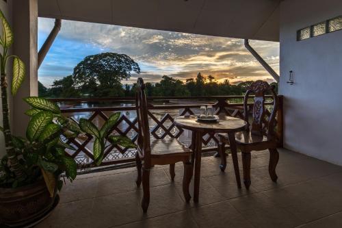 a table and chairs on a balcony with a view at BABA Guesthouse in Don Det