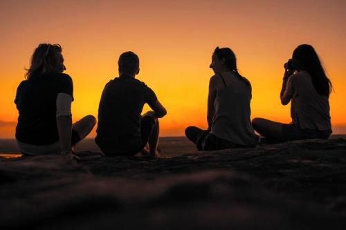 a group of people sitting on a rock watching the sunset at Cooinda Lodge Kakadu in Jabiru