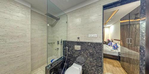 a bathroom with a shower with a toilet and a bed at The Aanandam Hotel Resort in Itārsi