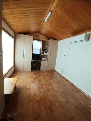a living room with a wooden ceiling and a wooden floor at The Red House in Sokcho