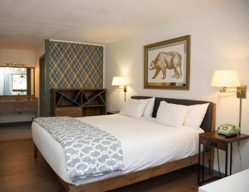 a bedroom with a large white bed with a picture of a elephant at The Occidental Lodge in Occidental