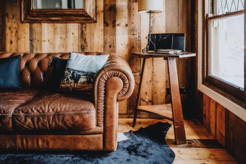 a living room with a brown leather couch and a television at The Dairy in Castlemaine