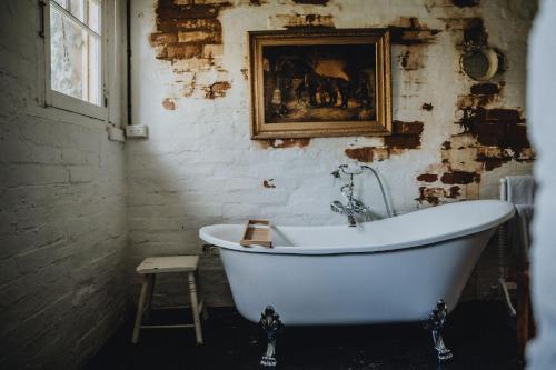 a bath tub in a room with a painting on the wall at The Dairy in Castlemaine