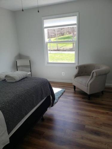 a bedroom with a bed and a chair and a window at Red River Gorge Creekside, New*Spacious *2 baths! in Stanton