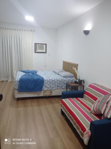 a bedroom with two beds and a couch at Flat Palladim in São Vicente