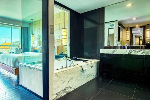 a large bathroom with a tub and a bed at The Sakala Resort Bali All Suites in Nusa Dua