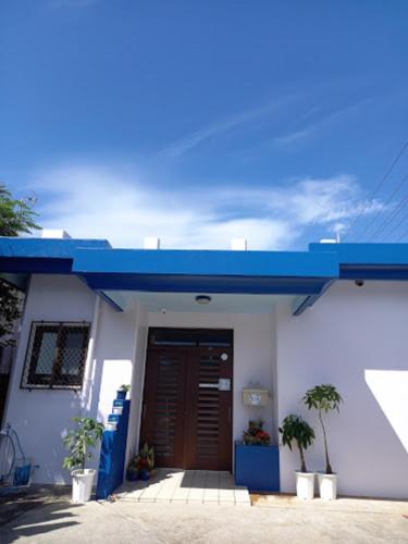 a white building with a blue roof and a door at Pension Hanadama - Vacation STAY 67585v in Arazato