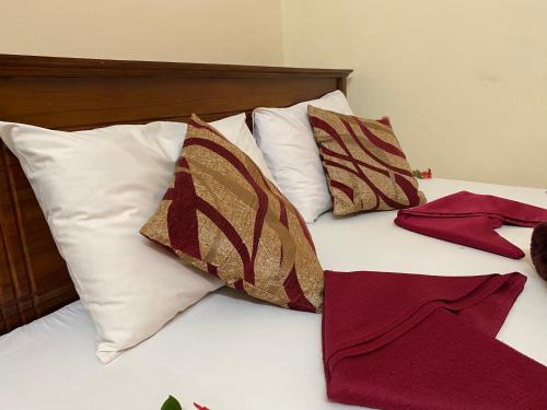 a bed with white pillows and red and brown and white pillows at Yal's Town Inn in Jaffna