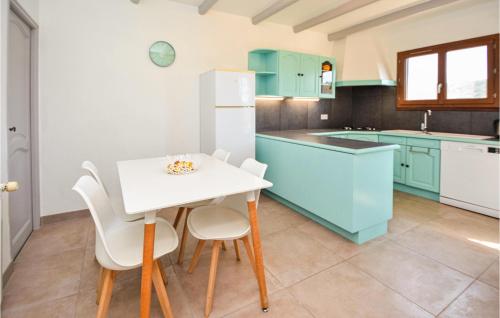 une cuisine avec des placards bleus et une table et des chaises blanches dans l'établissement Amazing Home In Les-Salles-Du-Gardon, à Les Salles-du-Gardon