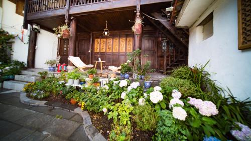 a garden with flowers in front of a building at Tuo Tuo Guest House in Lijiang