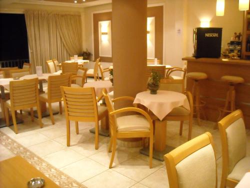 un comedor con mesas y sillas en un restaurante en Iris Hotel, en Nea Kalikratia