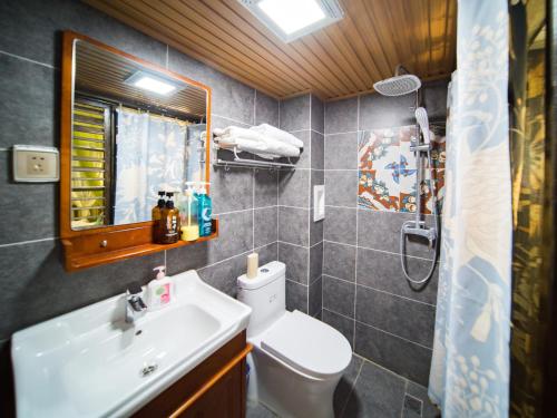 a bathroom with a sink and a toilet and a mirror at Tuo Tuo Guest House in Lijiang