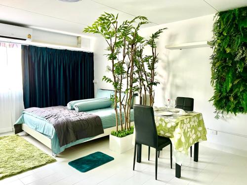 暖武里的住宿－C9 Popula Condo by Prathomlerk，一间卧室配有一张床、一张桌子和植物