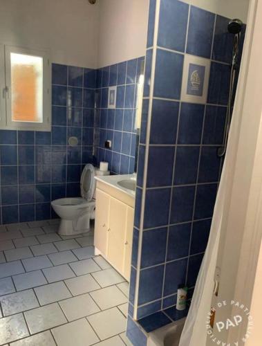 La salle de bains est pourvue de carrelage bleu, de toilettes et d'un lavabo. dans l'établissement Maisonnette, à Santa-Reparata-di-Balagna