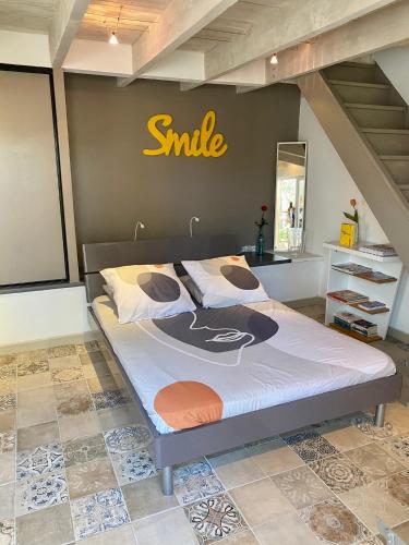 - un grand lit avec un signe de sourire sur le mur dans l'établissement Studio Tudo Bem, à Villeneuve-lès-Avignon