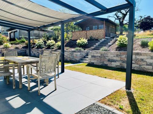 um pátio com uma mesa e cadeiras sob uma pérgola em Ferienhaus Traumzeit em NeuhÃ¼tten