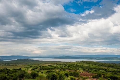 a view of a field and a lake under a cloudy sky at Lake Nakuru Sopa Lodge in Nakuru