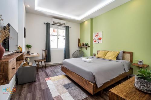 ホーチミン・シティにあるHoLo Central Saigon - Serviced HomeStayの緑の壁のベッドルーム1室(ベッド1台付)