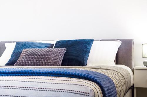 a bed with blue and white pillows on it at Studijos tipo apartamentai Tauragėje in Tauragė