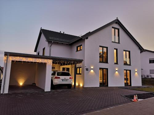 a white house with a car parked in a driveway at -Neubau- 30qm Dach-Apartment in Fulda