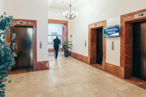 a man walking down a hallway in a building at Almog Haifa Israel Apartments מגדלי חוף הכרמל in Haifa