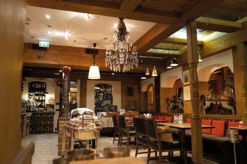 a restaurant with tables and chairs and a chandelier at Ringhotel Alpenhof - Patchworkhotel in Augsburg