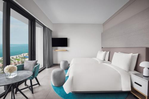 a bedroom with a large white bed and a table and chairs at Mövenpick Resort Al Marjan Island in Ras al Khaimah